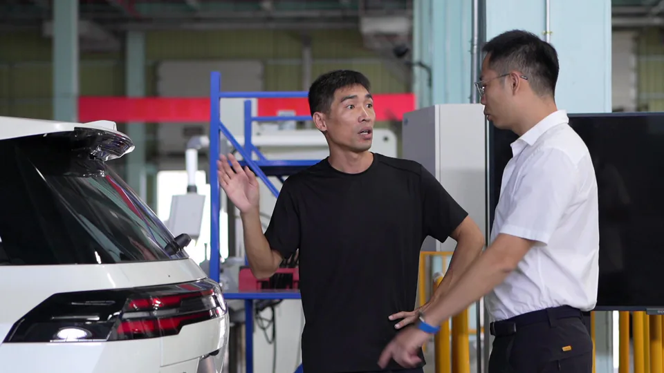 Two people discussing a vehicle at an automotive worksite